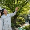 庭木の剪定方法を相談する依頼者と作業中の日本人剪定業者